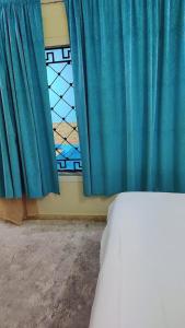 1 dormitorio con cortina azul y ventana en شاليهات ستي لاند, en Taif