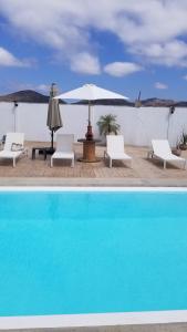 a pool with two chairs and an umbrella and a table at Cabañas Los Laureles ruta del vino in Ensenada