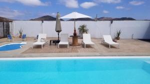 a group of chairs and an umbrella next to a pool at Cabañas Los Laureles ruta del vino in Ensenada