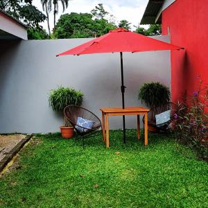 a table and two chairs with a red umbrella at Casa vista de luna in Guaria