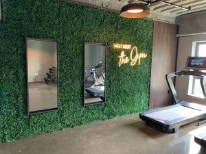 a gym with a green wall with mirrors and a treadmill at Modern Furnished Apartment in Heart of Quincy in Quincy