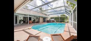 a large swimming pool with two chairs and a house at Siesta Key Home with pool/hot tub 12 min to beach in Sarasota