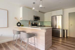 a kitchen with a counter with stools and a refrigerator at Modern Furnished Apartment in Heart of Quincy in Quincy