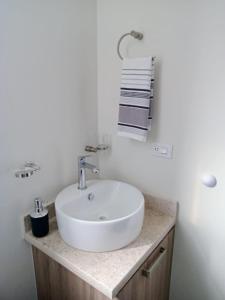 a white bathroom with a sink and towels at Casa Valtierra, La Paz in La Paz