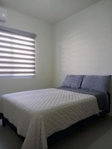 uma cama num quarto branco com uma janela em Casa Valtierra, La Paz em La Paz
