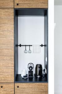 a cupboard with a coffee maker and a tea kettle at Apartamenty Solo na Molo in Sopot