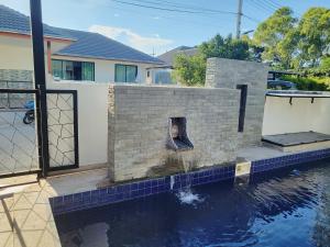 a pool of water with a brick fireplace at E villa , private pool villa for your family in Hua Hin