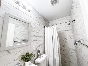 baño blanco con ducha y lavamanos en Cheerful & Modern Home w/ a Walkout Deck Area, en Glenside
