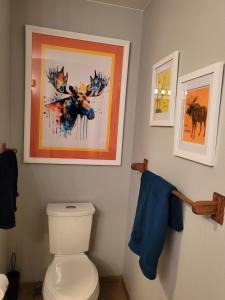 baño con aseo y una pintura en la pared en Moose Valley Inn, en Palmer