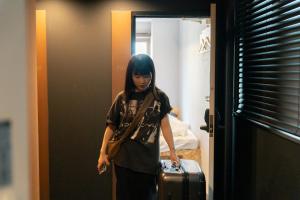Eine Frau, die mit einem Koffer in ein Zimmer geht. in der Unterkunft 3U NAMBA MINAMI by DOYANEN in Osaka