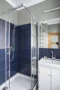a blue tiled bathroom with a shower and a sink at Apartamenty Solo na Molo in Sopot