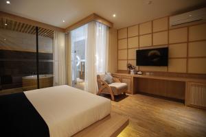- une chambre avec un lit, une télévision et une chaise dans l'établissement The Arch Phuket Hotel, à Ban Ket Ho