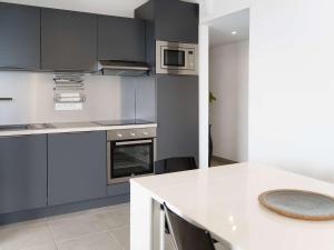 eine Küche mit grauen Schränken und einer weißen Arbeitsplatte in der Unterkunft Moderne T3 climatisé, 2 parkings, à 300m de la plage - FR-1-409-165 in Narbonne + 13 Fotos