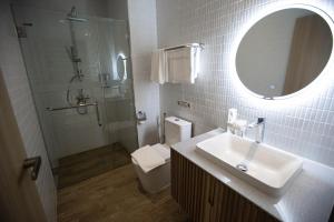 La salle de bains est pourvue d'un lavabo, de toilettes et d'un miroir. dans l'établissement The Arch Phuket Hotel, à Ban Ket Ho