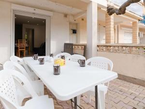 una mesa blanca y sillas blancas en el patio en Appartement Fleury-Saint-Pierre-la-Mer, 3 pièces, 5 personnes - FR-1-409-204, en Fleury