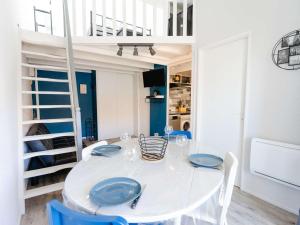 uma sala de jantar branca com uma mesa branca e cadeiras azuis em Appartement Narbonne, 2 pièces, 6 personnes - FR-1-409-243 em Narbona