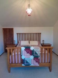 a bedroom with a wooden bed and a chandelier at The Loft at The Last Straw in Nelson