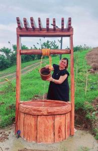 una mujer está de pie junto a una estructura de madera en Guillen Plantaciones Resort Farm, en Cebú