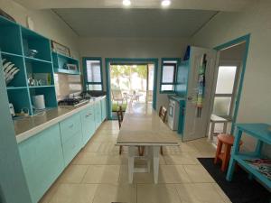 a kitchen with blue cabinets and a table in it at ShineAwayHomes -AC Beachfront RAROTONGA in Matavera