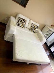 a white couch with pillows on it in a room at Apto com VISTA do Pão de Açúcar, VARANDA, PISCINA, SAUNA, ACADEMIA, COZINHA COMPLETA, GARAGEM, PORTARIA 24h e MINI MERCADO in Niterói