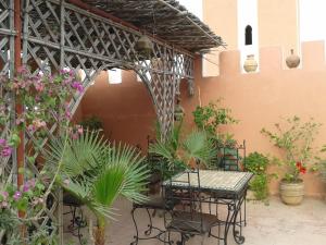 eine Terrasse mit einem Tisch, Stühlen und Pflanzen in der Unterkunft Chambres d'Hôtes les amis in Taroudant