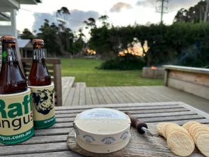 duas garrafas de cerveja e bolachas numa mesa de madeira em PepperTree Farm Stay em Grassy