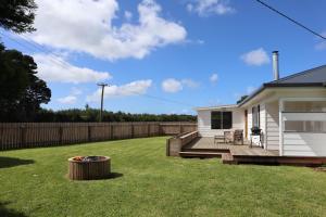 un patio trasero con una casa blanca y una terraza de madera en PepperTree Farm Stay, en Grassy