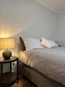 a bedroom with a bed with a lamp on a table at PepperTree Farm Stay in Grassy