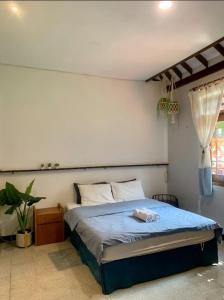 a bedroom with a bed with blue sheets and a window at Rumah Canda in Bandung