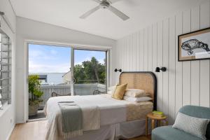 a bedroom with a bed and a window and a chair at The Bunkie @ Ethel & Odes in Bundeena