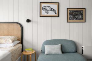 a bedroom with a chair and a bed and framed pictures at The Bunkie @ Ethel & Odes in Bundeena
