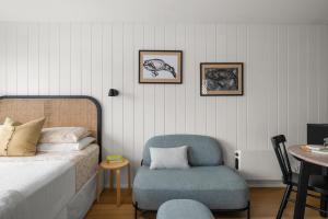 a bedroom with a bed and a chair and a table at The Bunkie @ Ethel & Odes in Bundeena