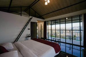 1 dormitorio con cama y ventana grande en The Hillside Cottages, en Kanatal