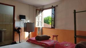 a bedroom with a bed and a window and a television at Pousada do Tie - Rio Preto MG in São José do Rio Preto