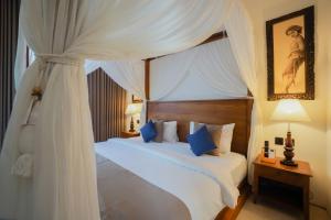 a bedroom with a white canopy bed with blue pillows at Villa Bulan Bali in Jimbaran