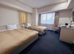 a hotel room with two beds and a desk at Nissei Hotel Fukuoka in Fukuoka