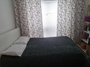 a bedroom with a bed with a black blanket and a window at large room for 2 sofa and TV in Newhaven
