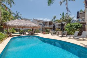 a swimming pool with chairs and a table at Clearwater Noosa Resort in Noosaville