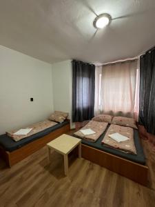 a room with two beds and a table in it at Peregrino Vendégház in Budaörs