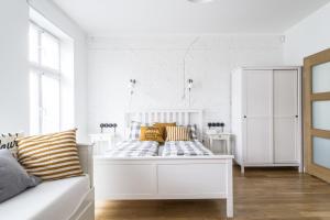 a white bedroom with a bed with yellow pillows at Apartamenty Solo na Molo in Sopot