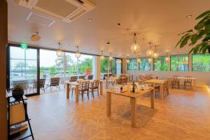 um restaurante com mesas e cadeiras e janelas grandes em セトノウツツ em Suo Oshima