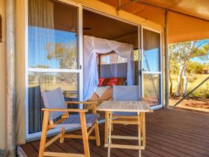 - une terrasse couverte avec 2 chaises, une table et un lit dans l'établissement Karijini Eco Retreat, à Karijini