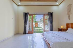 a bedroom with a bed and a sliding glass door at Sandz House in Jembrana
