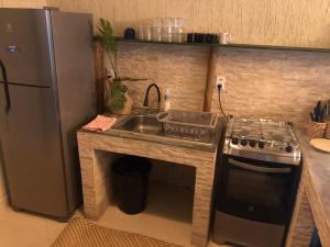 a kitchen with a sink and a stove and a refrigerator at Casita Cumbuco in Cumbuco