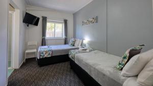 a hotel room with two beds and a tv at Oasis Motel in Peak Hill +27 photos
