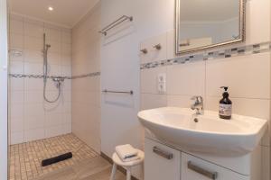 a white bathroom with a sink and a shower at FeWo Haus Friesenkind in Garding +20 photos