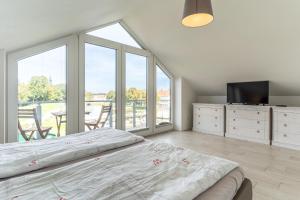 ein Schlafzimmer mit einem Bett und einem TV sowie einige Fenster in der Unterkunft Poller 23-Haus Alte Werft in Tönning