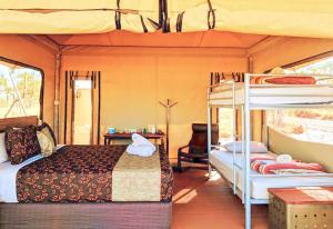 a bedroom with a bed and bunk beds in a bus at Karijini Eco Retreat in Karijini