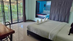 a bedroom with a large white bed with a desk and window at Na Na Doo Homestay in Chiang Rai