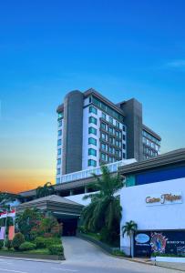 a large building with palm trees in front of it at Grand Regal Hotel Davao in Davao City